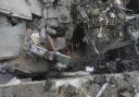 Palestinians look at the destruction after an Israeli strike on residential building in Rafa