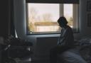 Side view of a woman sitting in her bedroom - negative emotion.