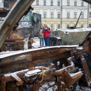People look upon destroyed Russian military vehicles in the bitter coldness of Kyiv’s winter