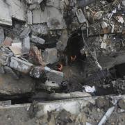 Palestinians look at the destruction after an Israeli strike on residential building in Rafa