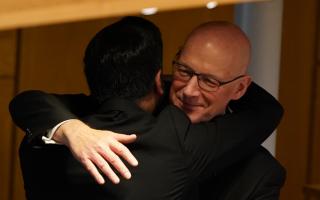 John Swinney, Scotland's next first minister, embraces his predecessor Humza Yousaf in the Holyrood chamber