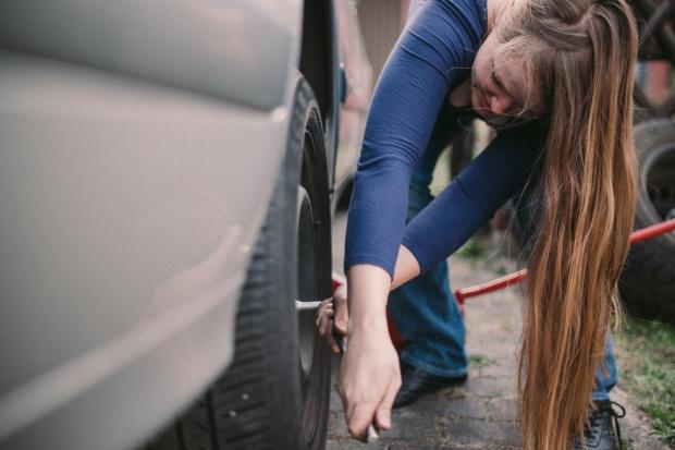 Not sure if a woman needs help changing a tyre... how about just asking them?