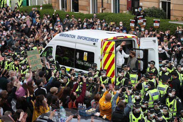 One of two men are released from the back of an Immigration Enforcement van accompanied by Mohammad Asif, director of the Afghan Human Rights Foundation, in Kenmure Street, Glasgow which is surrounded by protesters. Picture date: Thursday May 13, 2021.