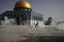 A Palestinian man run away from tear gas during clashes with Israeli security forces in front of the Dome of the Rock Mosque at the Al Aqsa Mosque compound in Jerusalem's Old City Monday, May 10