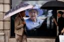 People walk past a picture of Britain's late Queen Elizabeth II on September 13, 2022