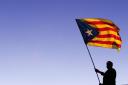 A man waves a Catalan Independence flag, know as 'Estelada', on a roof of a building