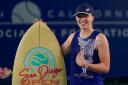 Iga Swiatek poses with her trophy and surfboard