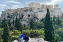 Tourists rest in the shadow of the Acropolis which towers over the Greek capital Athens