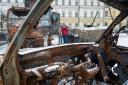 People look upon destroyed Russian military vehicles in the bitter coldness of Kyiv’s winter