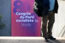 A man stands past a placard of the French left-wing Socialist Party's (PS - Parti socialiste) congress, on its opening day in Marseille, southern France
