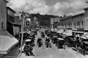 Horse-drawn carriages file past Main Street storefronts on Mackinac Island in Michigan