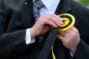 A man attaches his SNP rosette to his suit jacket on his way to vote