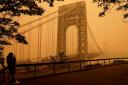 A man talks on his phone as he looks through the haze at the George Washington Bridge in Fort Lee, New Jersey (AP Photo/Seth Wenig)