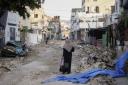 A Palestinian woman walks on a damaged road in the Jenin refugee camp in the West Bank, Wednesday, July 5, 2023