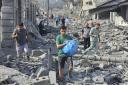 Palestinians walk through the rubble of buildings destroyed by Israeli airstrikes in Gaza City on Tuesday, Oct. 10