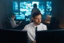 An employee of security, security, police, rescue service, FBI, CIA, sits at his workplace behind monitors. The man works behind two monitors, he studies the received information..
