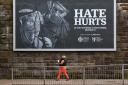 A member of the public walks past a hate crime billboard in Glasgow