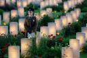 A soldier amongst military graves illuminated during part of a military-led vigil to commemorate the 100th anniversary of the beginning of the Battle of the Somme