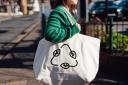 A young woman carrying a reusable shopping with a recycling symbol.