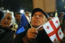 A demonstrator holds an EU and a Georgian national flags attending an opposition protest against the results of the parliamentary election in Tbilisi, Georgia