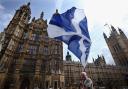 A man waves a Scottish flag outside the Houses of Parliament