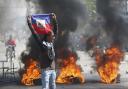 A demonstrator holds up an Haitian flag during protests demanding the resignation of Prime Minister Ariel Henry in Port-au-Prince, Haiti, Friday, March 1, 2024