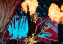 Billy Joe Armstrong plays on stage with the bright cartoons behind him
