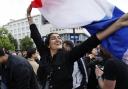 A woman waves the French flag as she reacts to projected results after the second round of the legislative elections