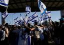 Protesters wave Israeli national flags in support of soldiers being questioned for detainee abuse, outside of the Sde Teiman military base in Israel (Tsafrir Abayov/AP)