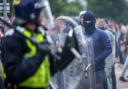 Riot police officers push back anti-migration protesters outside the Holiday Inn Express Hotel which is housing asylum seekers in Rotherham