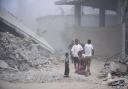 Palestinians walk through dust by the rubble of houses, destroyed by Israeli strikes in Khan Younis, Gaza Strip