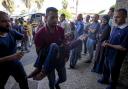 A Palestinian man carries an injured child after an Israeli airstrike in Deir al Balah, Gaza