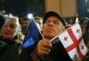 A demonstrator holds an EU and a Georgian national flags attending an opposition protest against the results of the parliamentary election in Tbilisi, Georgia