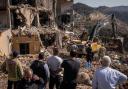 People watch as emergency response workers look for bodies in the rubble of a building that was hit by a Israeli airstrike