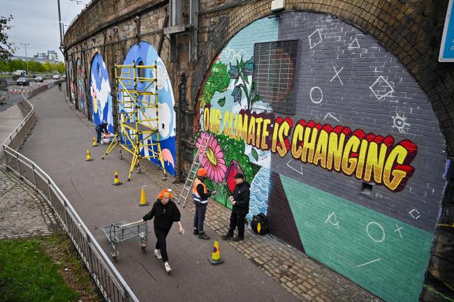 Artists paint a mural on a wall next to the Clydeside Expressway near the Scottish Events Centre (SEC) in Glasgow, Scotland. Photo: PA