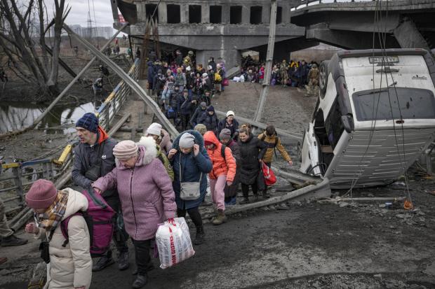 People cross on an improvised path under a bridge that was destroyed by Ukrainian troops designed to slow any Russian military advance, while fleeing the town of Irpin, Ukraine