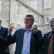 David MacMillan (centre) raises a glass as he toasts his Nobel prize win