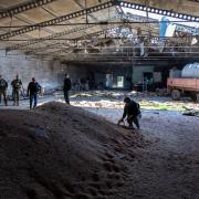 Soldiers and officials inspect a wheat grain warehouse in Ukraine that had been hit by a Russian shell