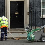 A street cleaner sweeps the road outside 10 Downing Street