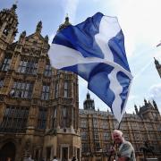 A man waves a Scottish flag outside the Houses of Parliament