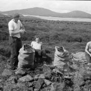 The book contains more than 100 contemporary black and white photographs, including this shot of men taking a break during peat cutting on the island of Stromay
