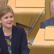 SNP MSPs Nicola Sturgeon and John Mason laugh after the former is called 'first minister'