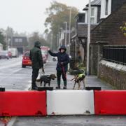 Dog walkers near a flood defence barrier erected on Church Street in the village of Edzell, Angus