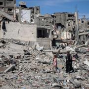 A Palestinian woman and girl walk through the rubble of destroyed homes in the wake of an Israeli attack