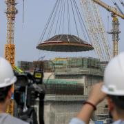 A 550-ton outer dome is hoisted into place at the construction site of the world's first commercial small modular reactor, Linglong One in China