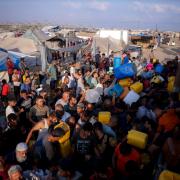Pictured: Palestinians displaced by the Israeli bombardment of the Gaza Strip queue for water at a makeshift tent camp in Khan Younis on Monday