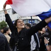 A woman waves the French flag as she reacts to projected results after the second round of the legislative elections