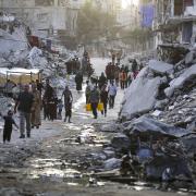 Displaced Palestinians walk through a dark streak of sewage flowing into the streets of the southern town of Khan Younis in the Gaza Strip