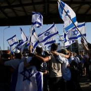 Protesters wave Israeli national flags in support of soldiers being questioned for detainee abuse, outside of the Sde Teiman military base in Israel (Tsafrir Abayov/AP)