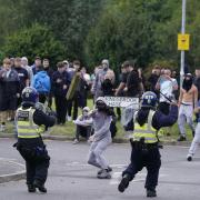 A rioter throws a fence post towards police officers during an anti-migrant rally outside a hotel in Rotherham, South Yorkshire on Sunday